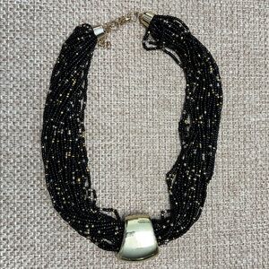 23 strand black seed bead necklace; copper accents. Gold focal slide. Weighted